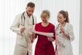 A team of four doctors standing in line at the clinic. Doctors read the patient`s tests.