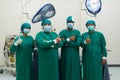 A team of four surgeons dressed in scrubs, standing amid the sterile environment of an operating room, they pose for a moment of