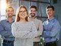 a team of four with a woman leader in the foreground stands in a modern office Royalty Free Stock Photo