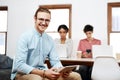 This team gets things done. Cropped portrait of a handsome young businessman sitting and using a tablet while his Royalty Free Stock Photo