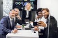 Team of good-looking smiling successful diverse corporate coworkers with mature female boss, posing on phone camera for