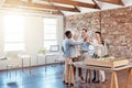 Team of happy architect engineers celebrating together with a high five after completing a small apartment complex model