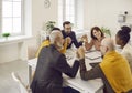 Team of happy business people sitting around an office table, holding hands and smiling Royalty Free Stock Photo