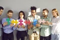 Team of happy young diverse business people connecting colorful jigsaw puzzle pieces Royalty Free Stock Photo