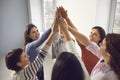 Team of happy young women joining hands, feeling united, confident and empowered