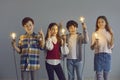 Group of creative smart little children holding light bulbs and pointing fingers up Royalty Free Stock Photo