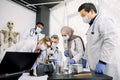 Team of lab workers, veterinarians, bio chemists examining tissues or blood sample using the microscope. Group of