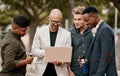 A team leader coaching his staff outdoors, standing and using a laptop. A group of male designers working on a start up Royalty Free Stock Photo