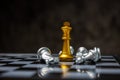 Gold king surrounded with silver chess pieces on chess board game competition with copy space on dark background Royalty Free Stock Photo