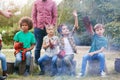 Team Leader With Group Of Children On Outdoor Activity Trip Toasting Marshmallows Over Camp Fire Royalty Free Stock Photo