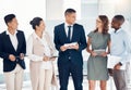 Team, leadership and business people standing in office talking, having conversation and discussion. Teamwork, diversity