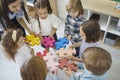 Team of little children together with their teacher join pieces of a jigsaw puzzle Royalty Free Stock Photo