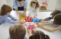 Team of little students with their teacher joining pieces of jigsaw puzzle in a lesson