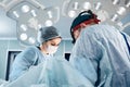 A team of male and female surgeons in a modern operating room, under a bright light, perform an operation, modern Royalty Free Stock Photo