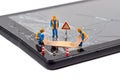 A team of miniature workmen repairing a broken mobile phone tablet touchscreen Royalty Free Stock Photo