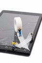 A team of miniature workmen repairing a broken mobile phone tablet touchscreen Royalty Free Stock Photo