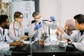 Team of multiethnic scientists in lab coats in modern laboratory conduct medical research in search of vaccine or new Royalty Free Stock Photo