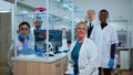 Team of multiethnic scientists sitting in laboratory looking at camera