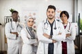 Team of multiracial doctors with crossed arms posing indoors