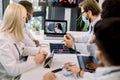 Team of multiracial experienced doctors in facial masks, having video conference with their young confident African Royalty Free Stock Photo