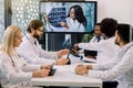 Team of multiracial experienced doctors or scientists, having video conference with their young confident African female