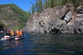 Team of people on an inflatable catamaran raft on a river canyon.