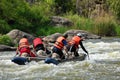 Team of people on an inflatable catamaran row up the stream in a thresholds.