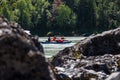 A team of people rafting in equipment, life jackets and helmets on a blue inflatable boat along the mountain river between the
