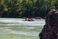 A team of people rafting in orange life jackets on an inflatable rubber boat of blue and yellow colors along a mountain river