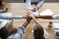 Team people stacking hands together over table engaged in teambuilding