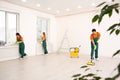 Team of janitors in uniforms cleaning room