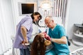 Team of professional male doctor dentist and his female assistant doing examination and treatment to young female Royalty Free Stock Photo