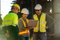 A team of professionals, civil engineers, architects and workers are using laptops at a freeway construction site. to inspect Royalty Free Stock Photo