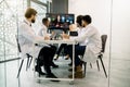 Team of qualified multiracial doctors having a medical discussion in a meeting room with big digital screen, sitting at Royalty Free Stock Photo