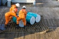 A team of riggers or roughnecks handling oil drum