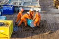 A team of riggers or roughnecks handling oil drum