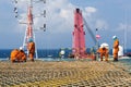 A team of riggers or roughnecks installing landing net on a helipad of a construction work barge