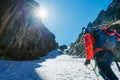 Team roping up woman dressed high altitude mountaineering clothes and harness climbing with backpack by snowy slope in the couloir Royalty Free Stock Photo