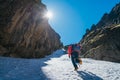 Team roping up woman dressed high altitude mountaineering clothes and harness climbing with backpack by snowy slope in the couloir Royalty Free Stock Photo