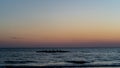 Rowing crew in silhouette on water against pastel sunset sky