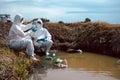 Team of scientists or biologists wears protective clothing to collect water samples from a natural water source with chemical-