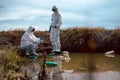 Team of scientists or biologists wears protective clothing to collect water samples from a natural water source with chemical-