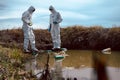 Team of scientists or biologists wears protective clothing to collect water samples from a natural water source with chemical-