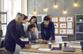 Team of business people standing at office table and looking at screen of laptop computer Royalty Free Stock Photo