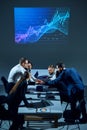 Team shakings hands for good cooperation. Office workers sit around conference table with digital stock chart displayed