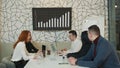 A team of smart people in the office discuss the company's growth and watch the company's infographics and growth on TV.