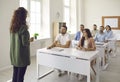 Business coach talking to happy adult students who are sitting at desks in classroom Royalty Free Stock Photo