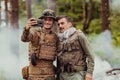 Team of soldiers and terrorist taking selfie with smartphone in the forest