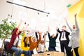 Team of successful multiethnic coworkers in modern office workplace throwing paper celebrating success. Diversity happines concept