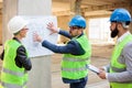 Team of architects and business partners looking at architectural drawings and blueprints.